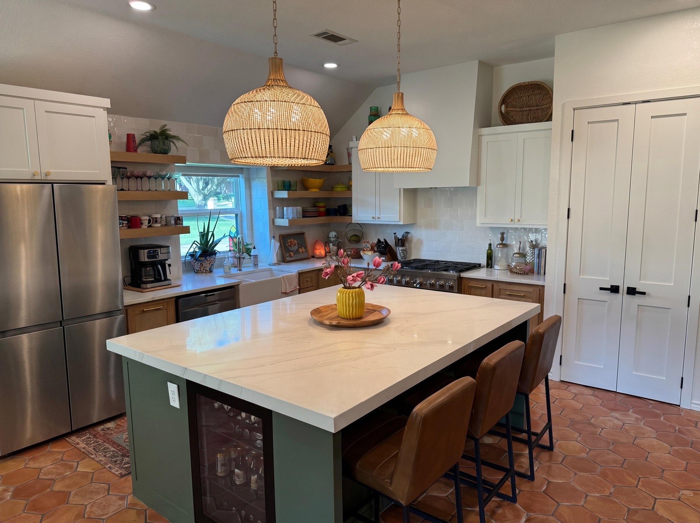 Renovated kitchen with a marble waterfall island, green cabinetry, and rattan pendant lighting